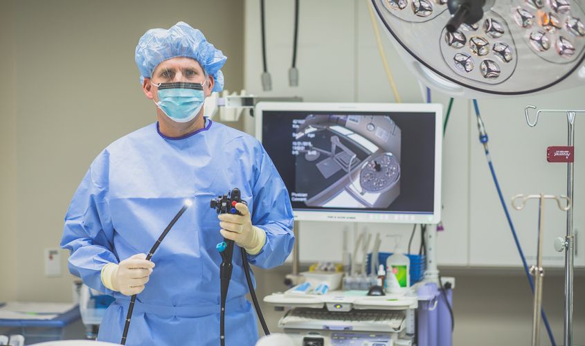 Doctor in surgical scrubs holding an illuminated endoscope in a medical procedure room News