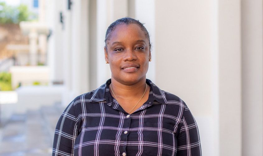 Smiling Black woman wearing a black and white plaid button-down shirt outdoors News