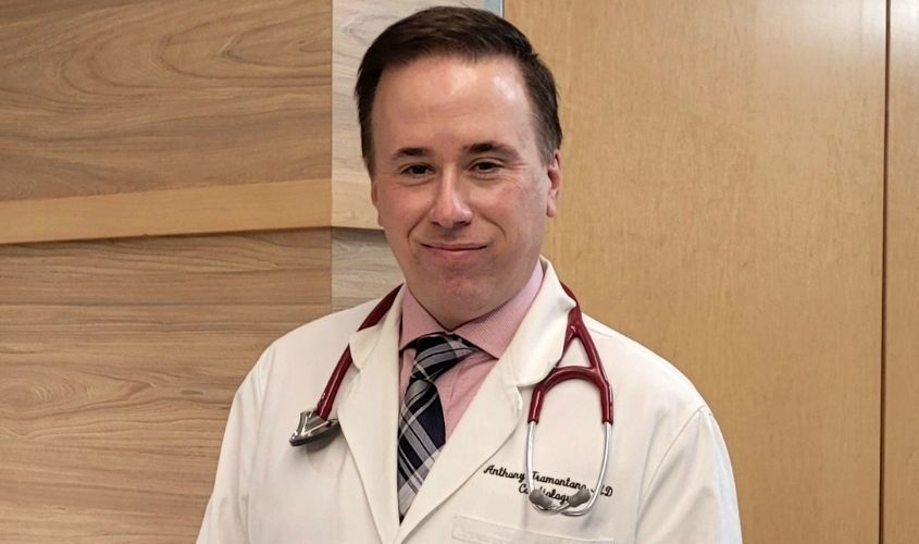 Dr. Anthony Tramontano, a cardiologist, smiling in a white lab coat with a stethoscope around his neck