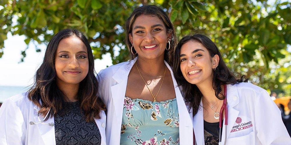 Diverse group of smiling SGU medical students|SGU medical students examine a patient during a community outreach event