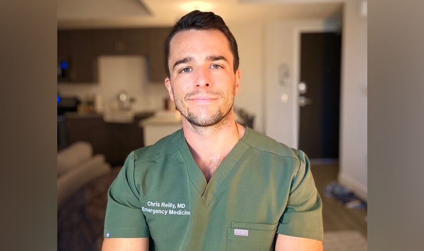 Chris Reilly, MD, an emergency medicine physician, smiling in green scrubs