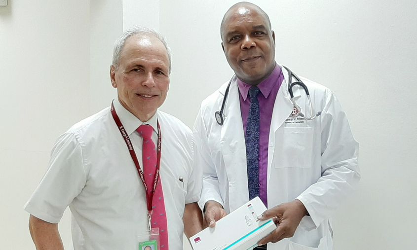 Two St. George's University medical professionals standing together and holding a medical testing kit box