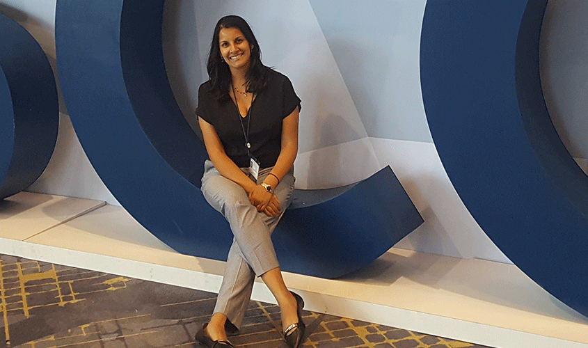 Woman smiling while sitting on a large blue curved sculpture at an indoor event News