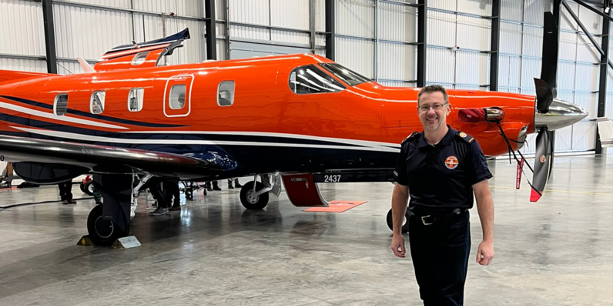 Dr. Beamont standing in front of a red airplane