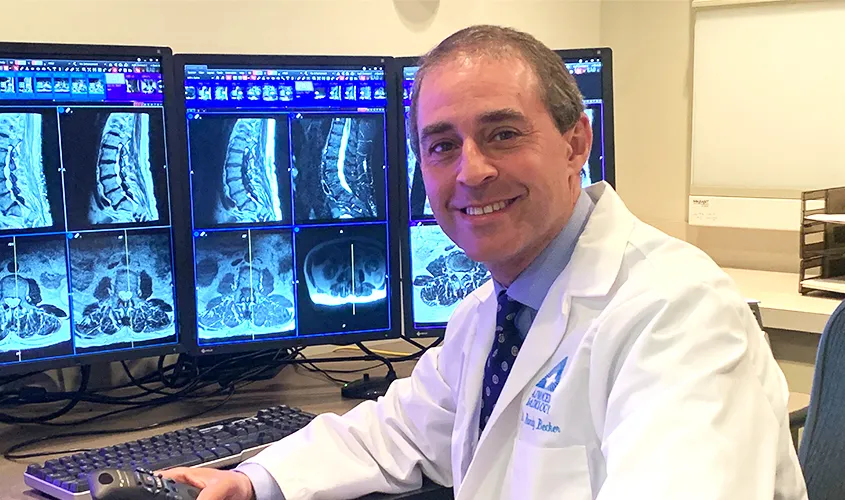 Dr. Randy Becker, SGU alumnus and radiologist, sitting beside the portable breast ultrasound units donated to Grenada
