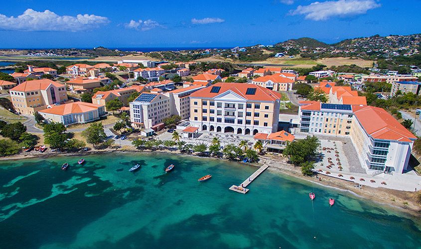 Aerial view of the campus at SGU in Grenada, showing Caribbean-sea waterfront and Georgian-inspired buildings.