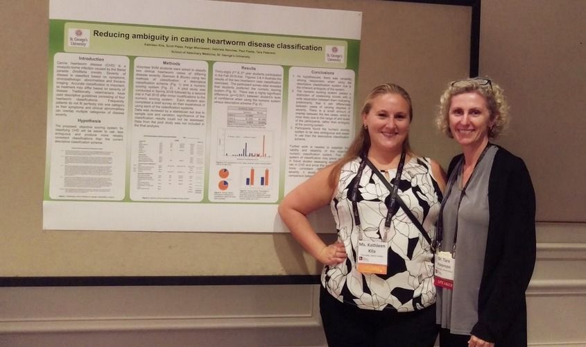Two women standing beside their research poster titled "Reducing ambiguity in canine heartworm disease classification