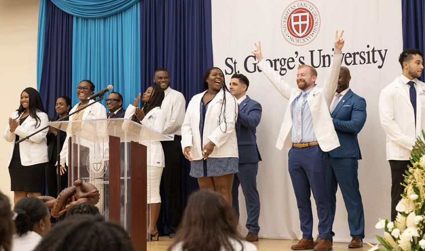 Medical students celebrate on stage during a St. George's University White Coat Ceremony