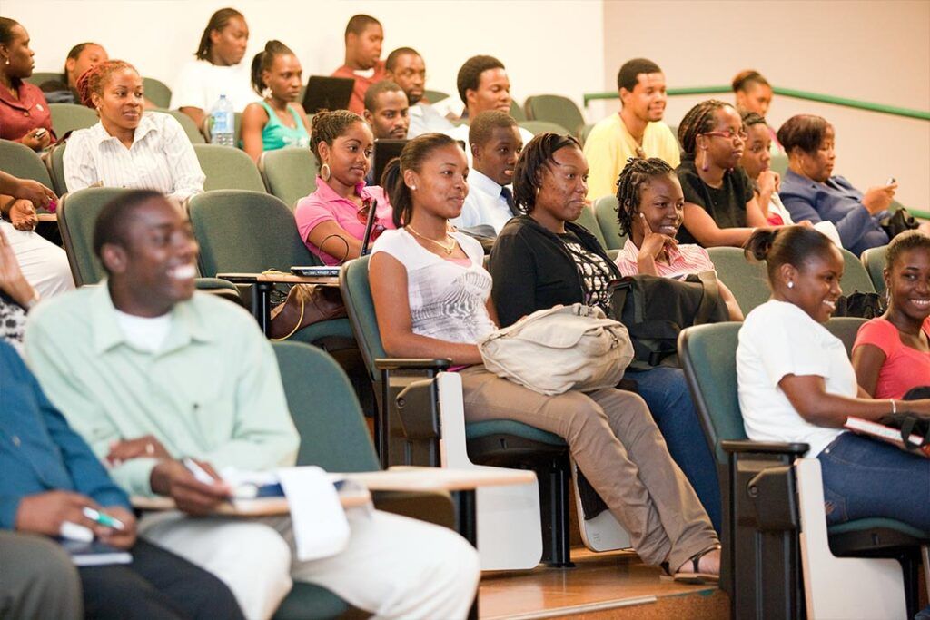 Students seated in tiered lecture hall rows listening attentively during a presentation