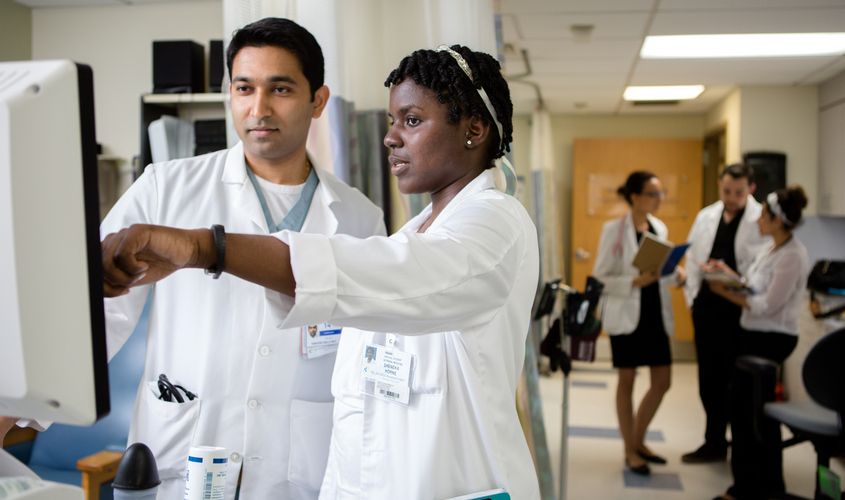 Medical professionals in lab coats reviewing information on a monitor in a hospital setting News
