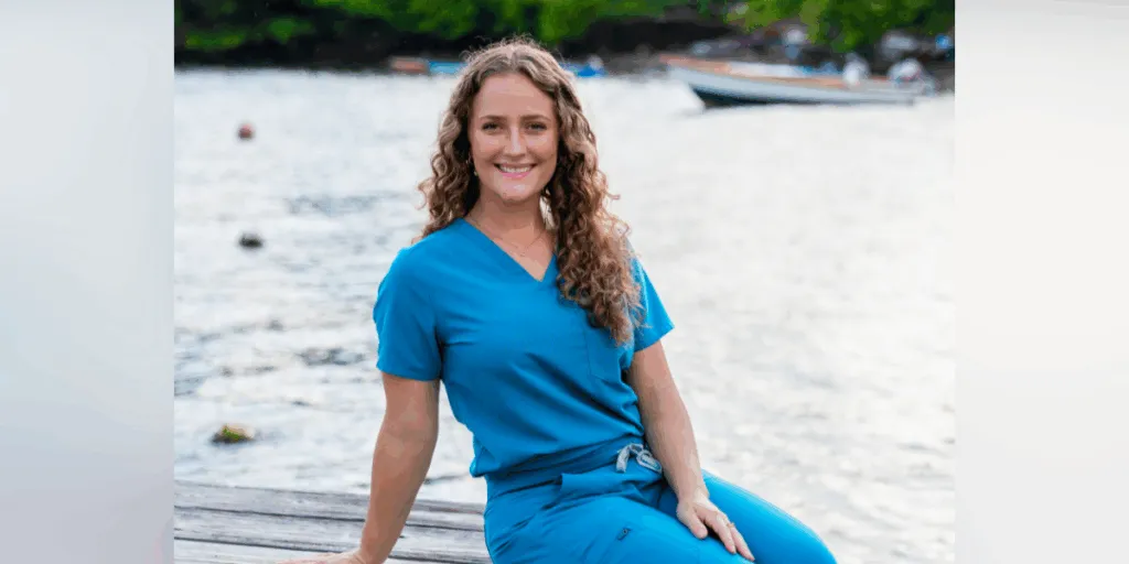 Deanna Boner, SGU SVM student, sits on a dock wearing scrubs