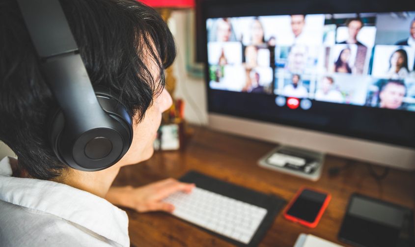 Person wearing headphones attends a group video conference on their computer