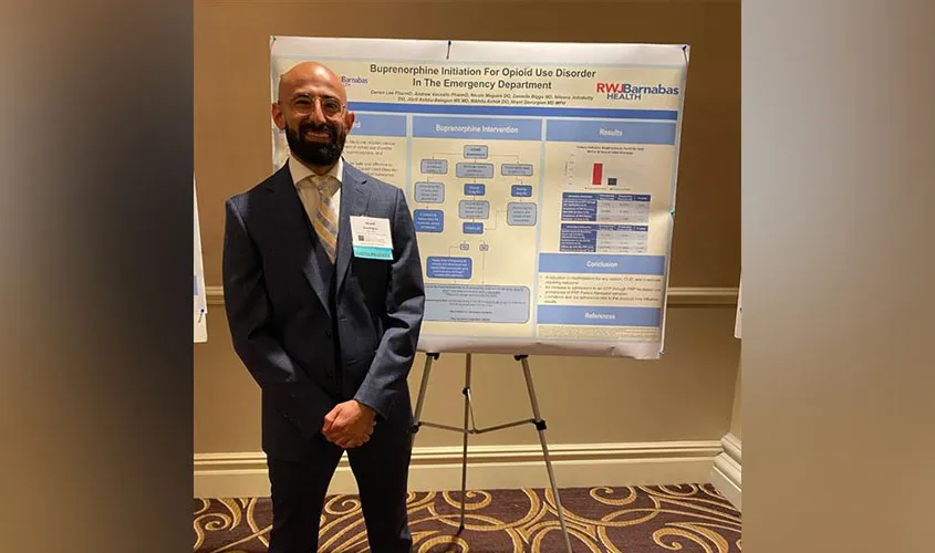 Presenter standing beside a medical poster on buprenorphine initiation for opioid use disorder in the emergency department