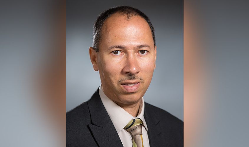 Portrait of a man wearing a dark suit and patterned tie against a neutral studio backdrop News