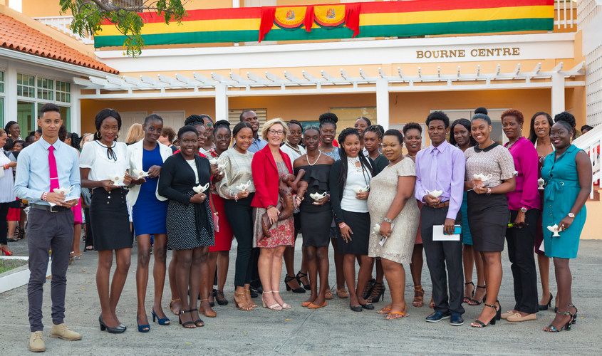 A group of students holding small oil lamps poses together outside the Bourne Centre