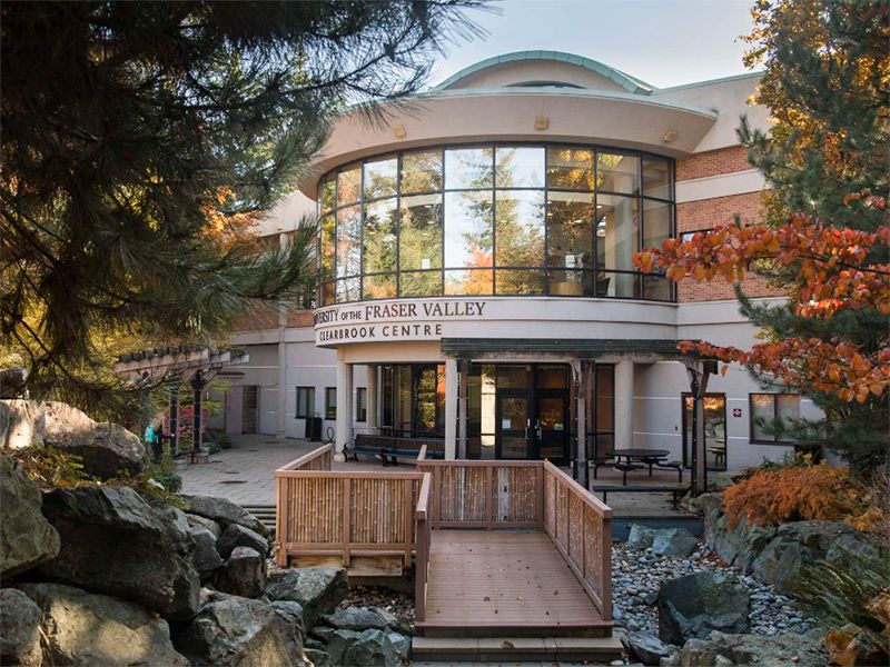 Wooden walkway leading to the University of the Fraser Valley Clearbrook Centre building with a curved glass facade