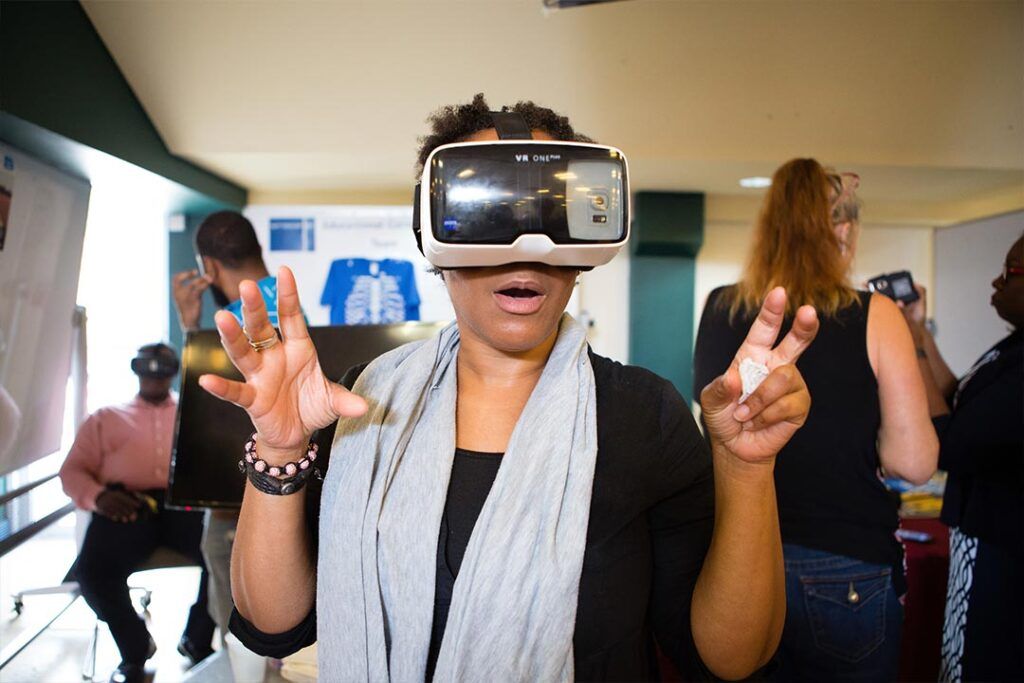 A woman wearing a VR headset reacts with amazement with her hands raised