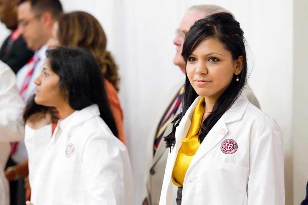 Portrait of an SGU student wearing a white coat with the WCC emblem
